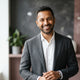 A professional portrait of a smiling man against a charcoal and dusty rose background, representing a satisfied customer.