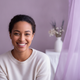 A diverse young mother smiles warmly, conveying trust and contentment.